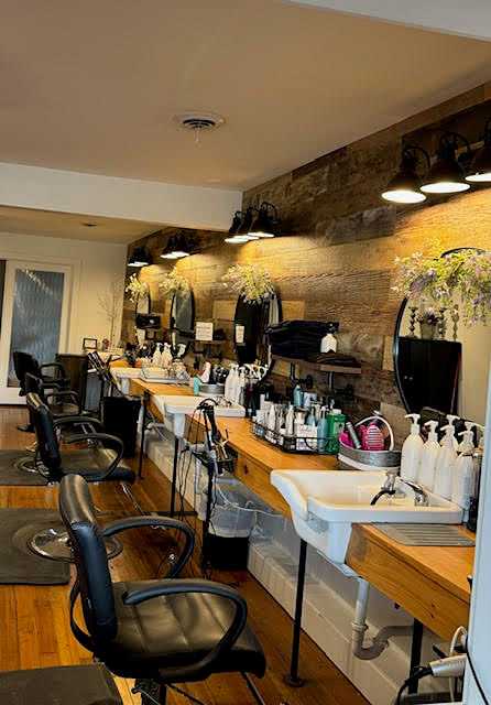 Modern salon with styling chairs, mirrors, and hair products neatly arranged on wooden counter.